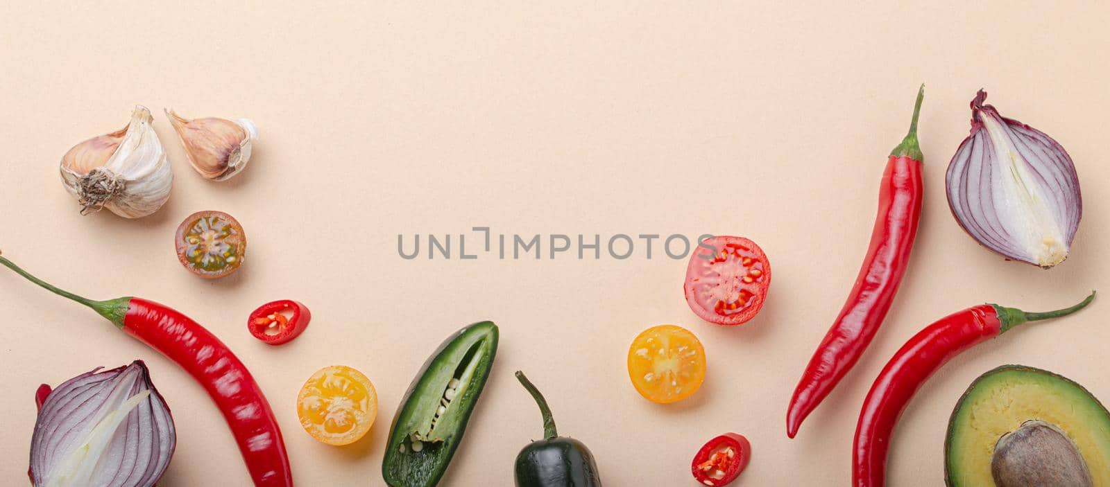 Creative cooking healthy organic food concept background made of colourful fruit and vegetables on beige background flat lay: tomatoes, peppers, avocado, onion, garlic top view with space for text.