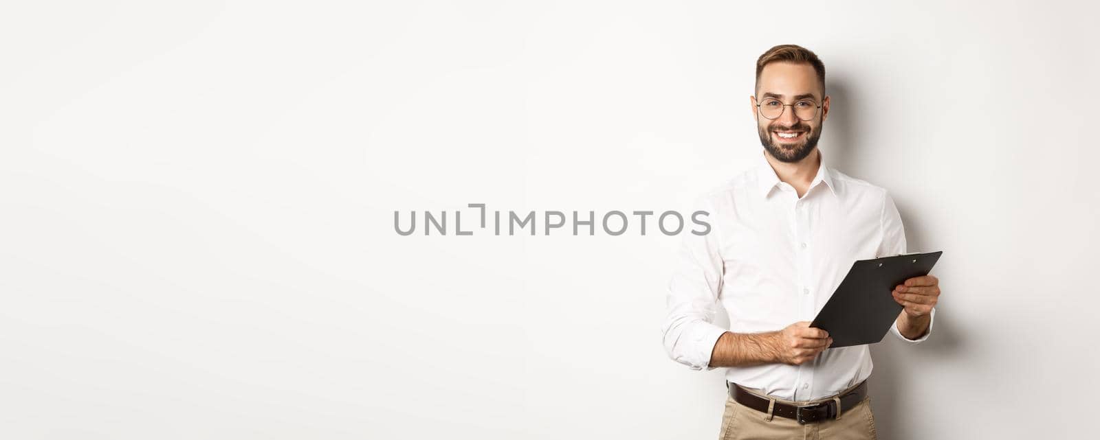 Handsome manager in glasses working, using clipboard, standing over white background.