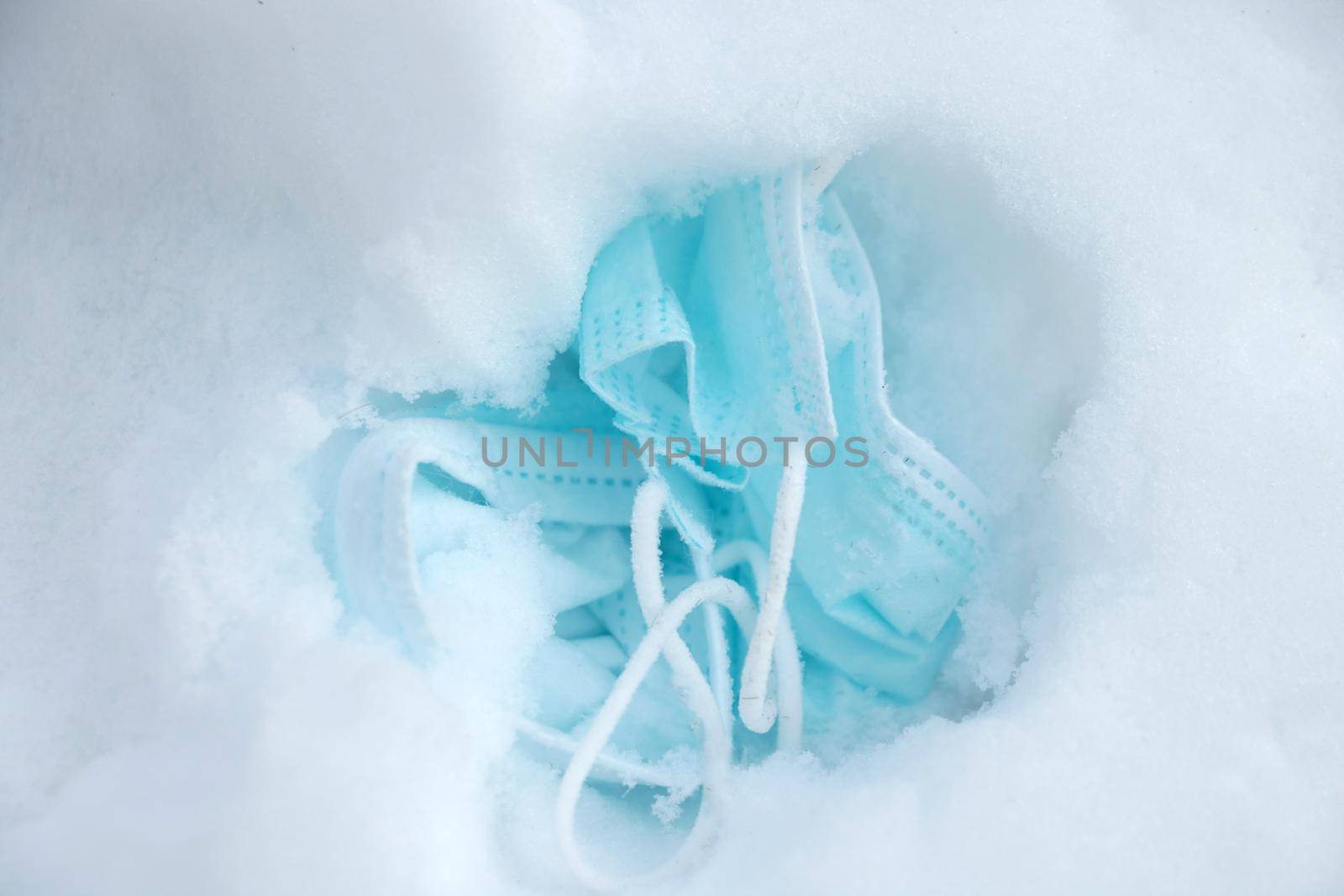 A used medical mask lies in the snow. Winter wave of coronavirus. The onset of an epidemic