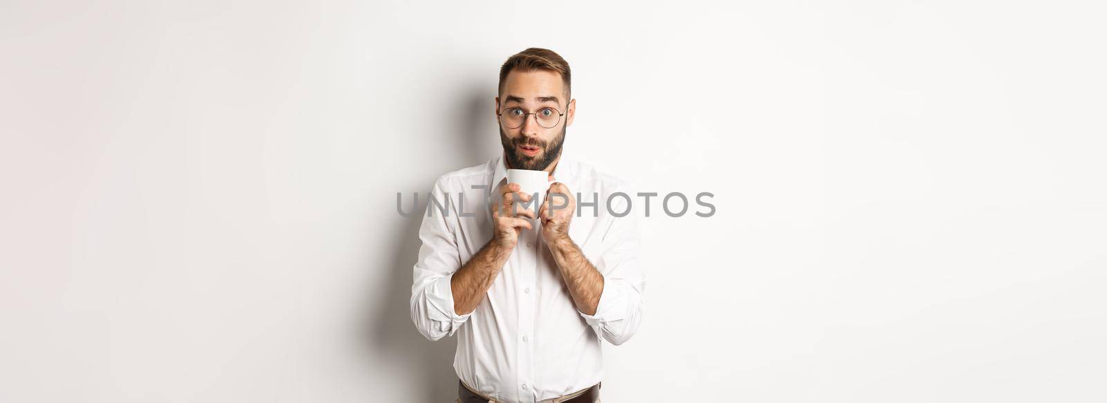 Happy office worker drinking hot coffee and looking excited, gossiping, standing over white background by Benzoix