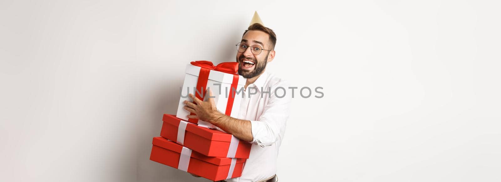 Holidays and celebration. Excited man having birthday party and receiving gifts, looking happy, standing over white background.