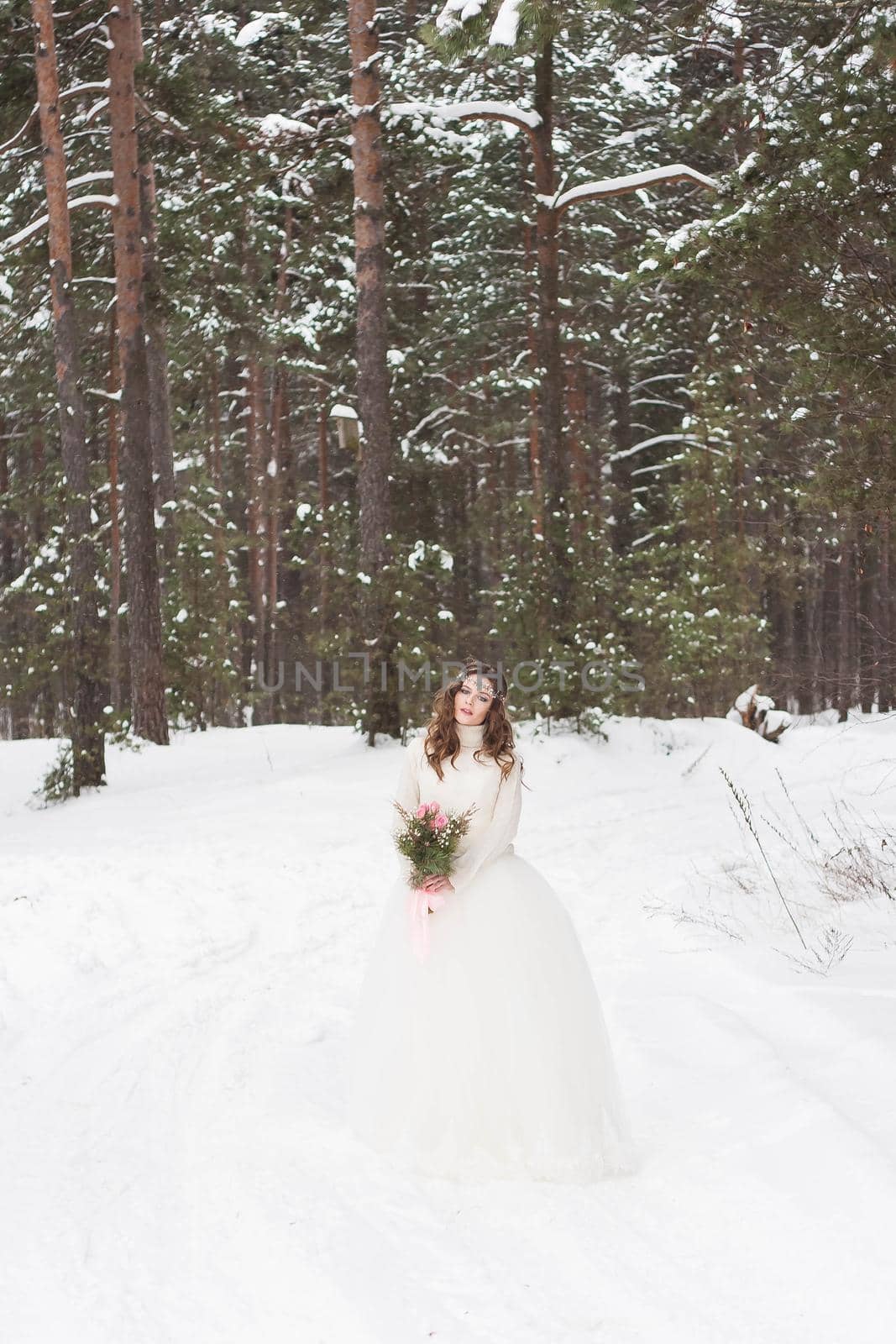 Beautiful bride in a white dress with a bouquet in a snow-covered winter forest. Portrait of the bride in nature by Annu1tochka