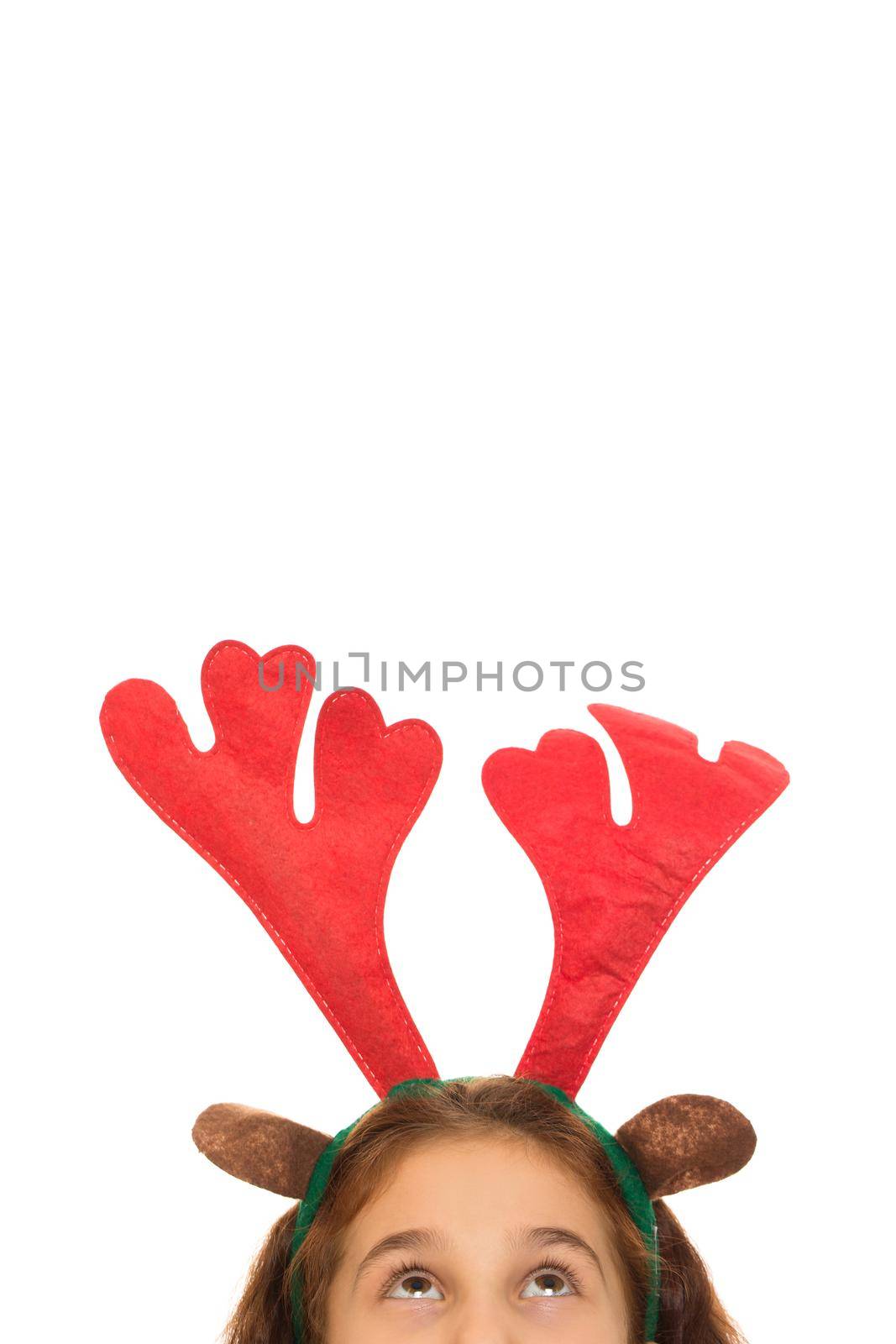 Vertical cropped shot of a little girl wearing Christmas raineer antlers looking at the copyspace above her isolated x-mas holidays news enjoyment childhood new year merry winter kids joy