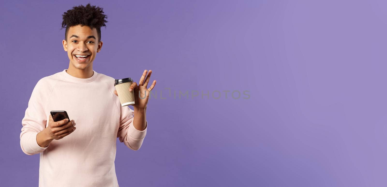 Portrait of cheerful young male student with cup of coffee and mobile phone, waving hand to say hi, smiling friendly as greeting person, meet classmate near university campus, purple background by Benzoix