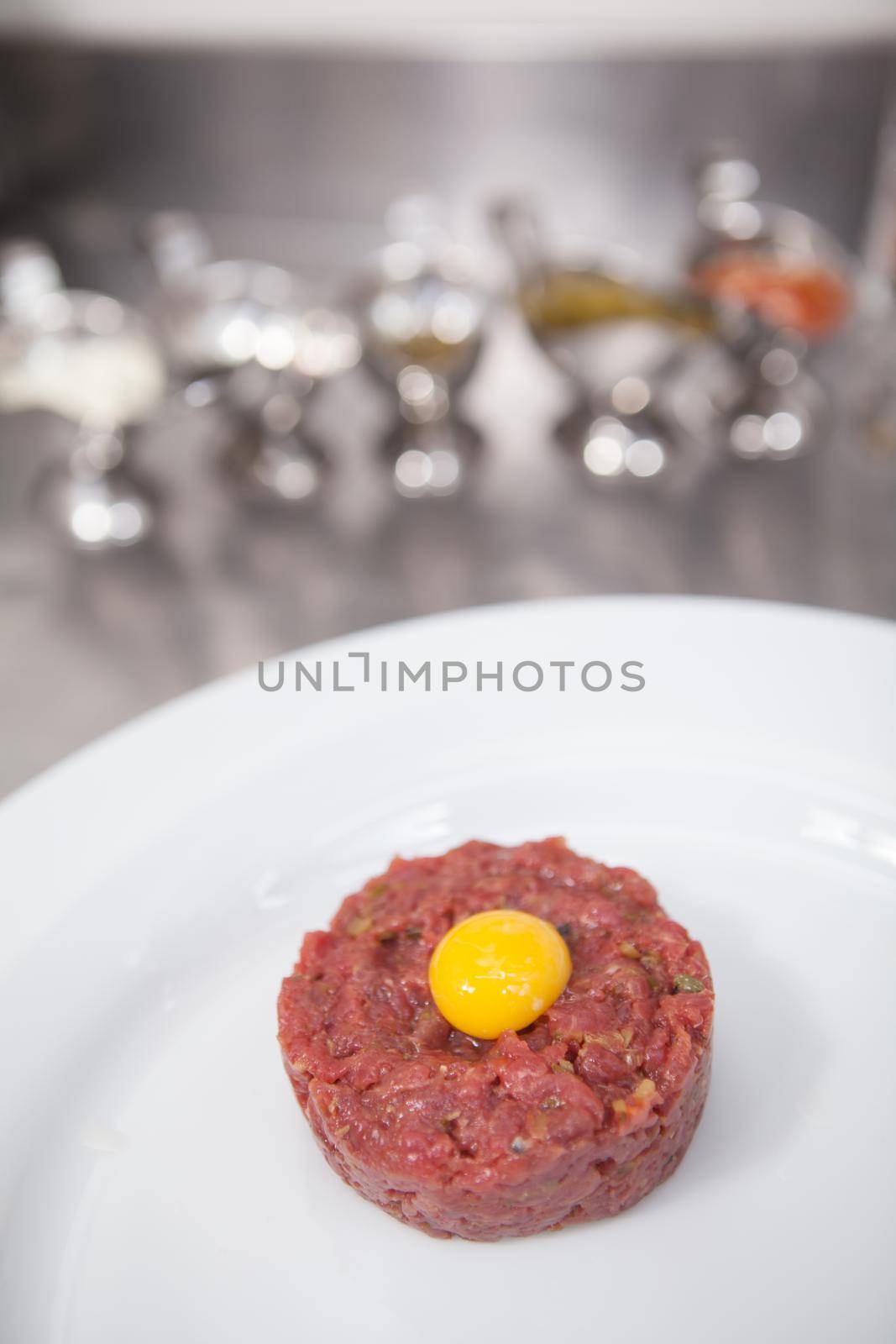 Vertical close up of beef tartar with raw quail egg on top, copy space