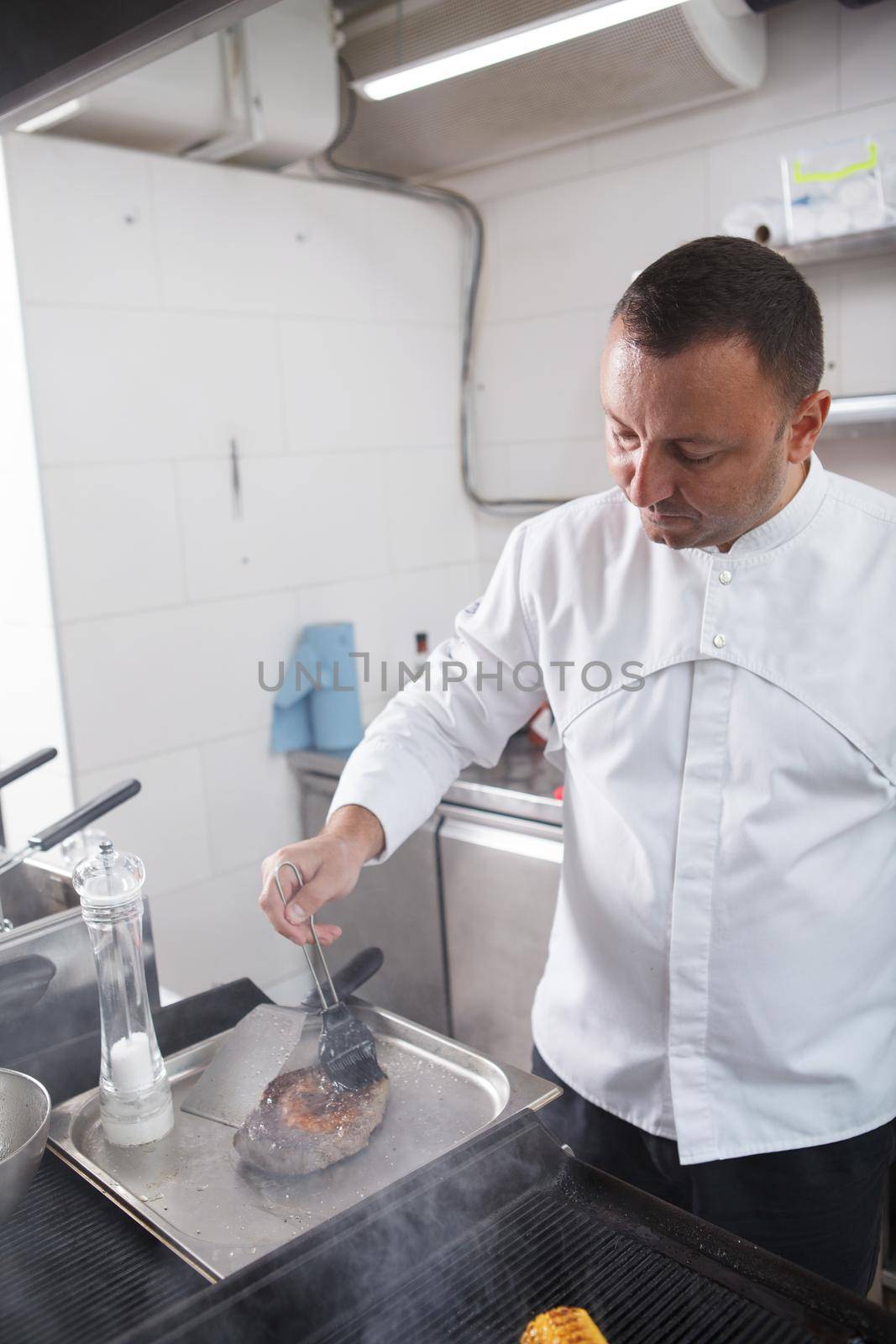 Vertical shot of chef preparing grilled beef steak at the restaurant