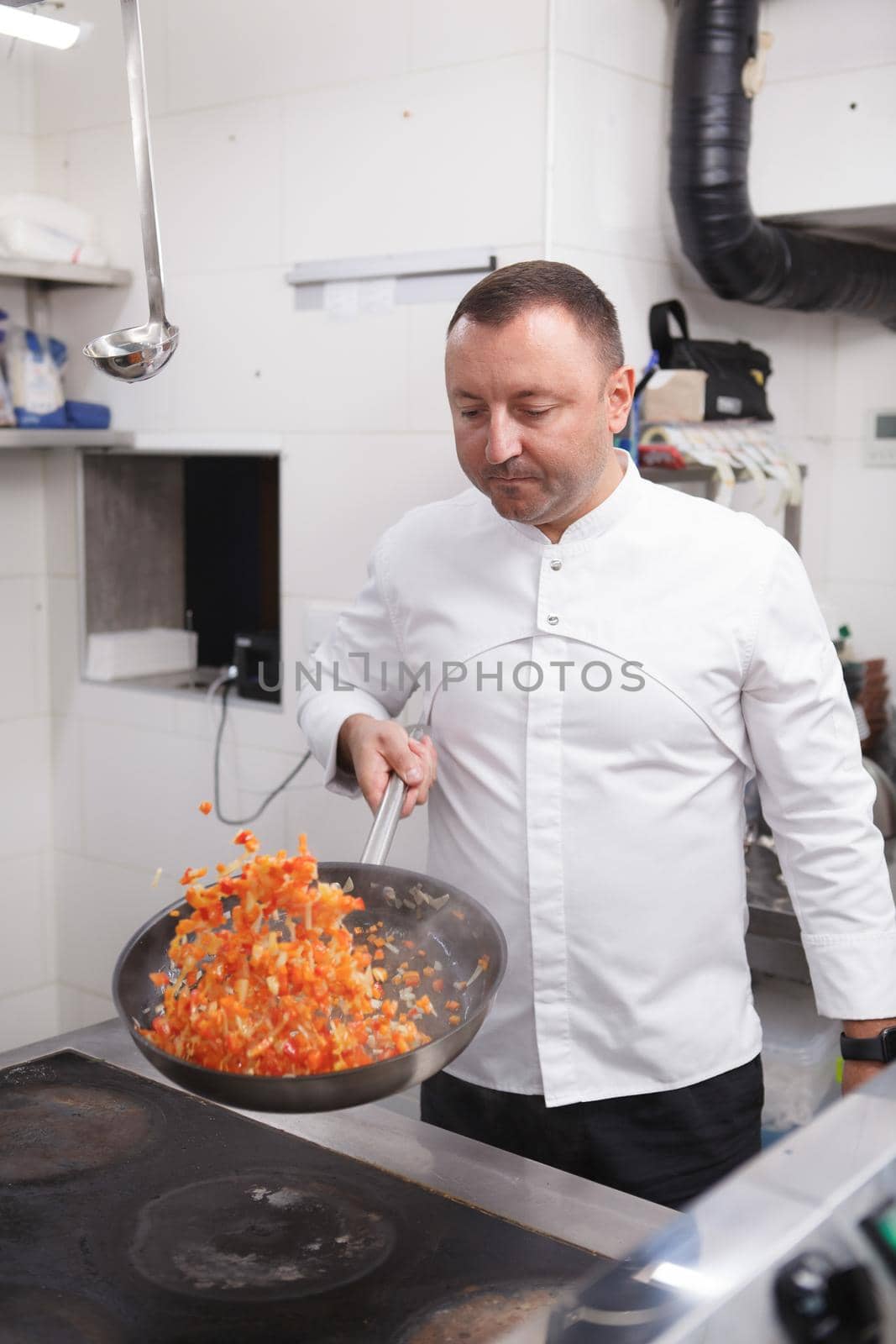 Vertical shot of a professional chef frying vegetables