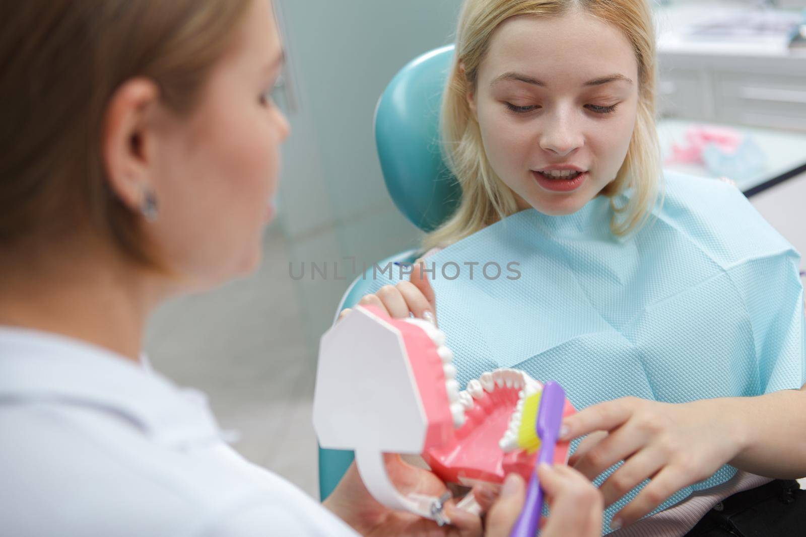 Female patient learning how to brush teeth correctly from her dentist