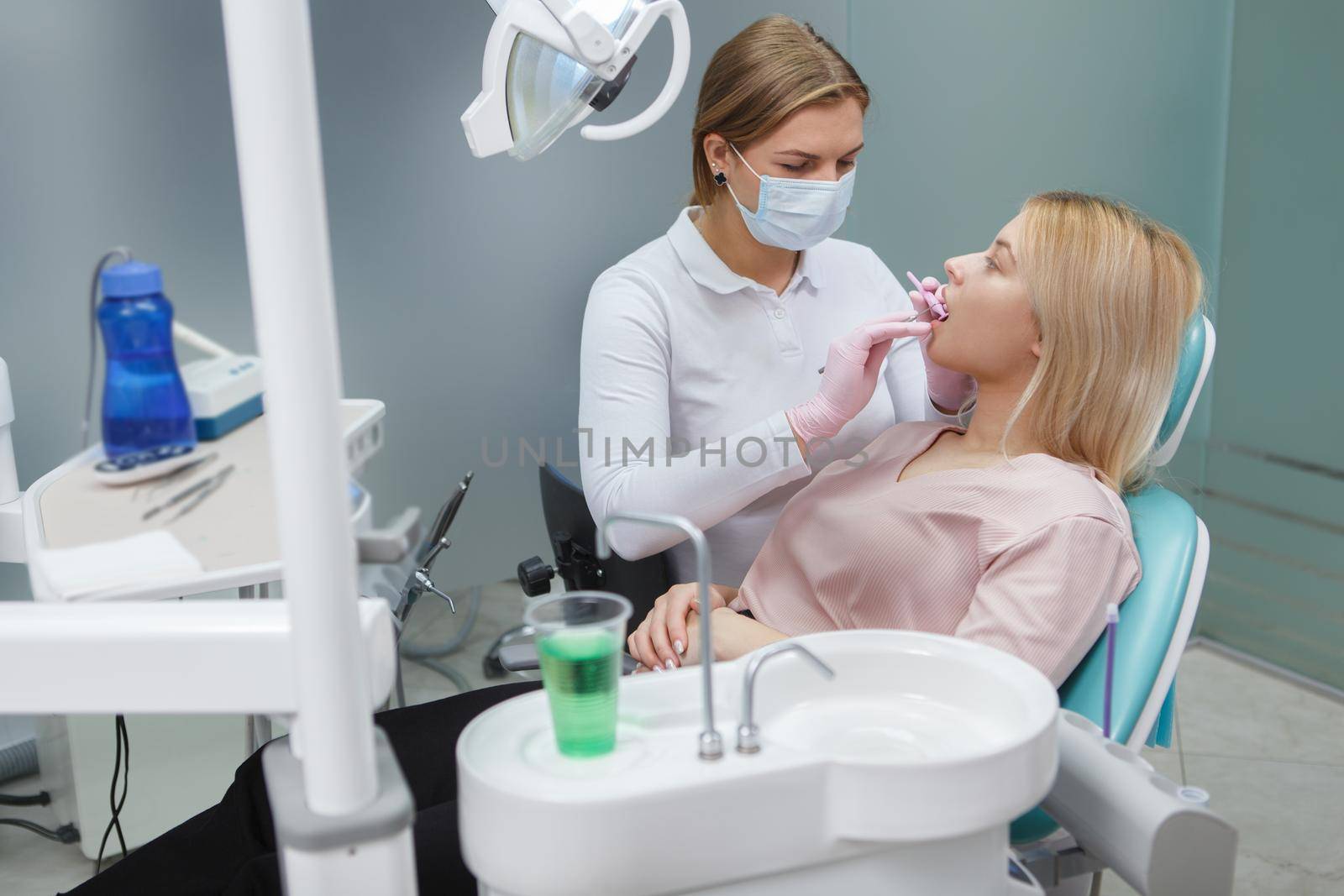 Female dentist working at her clinic, checking teeth of female patient