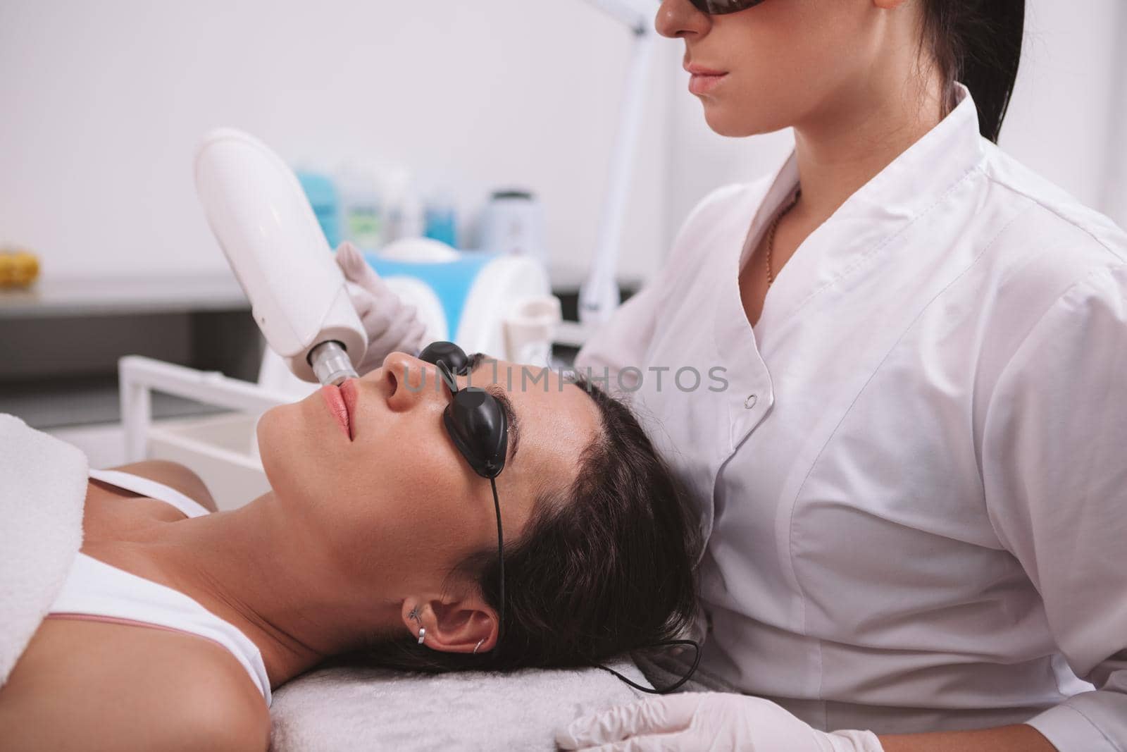 Cropped shot of a young woman getting facial hair removal laser treatment by professional dermatologist