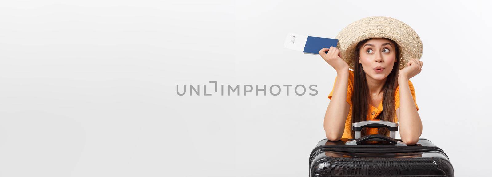 Travel concept. Studio portrait of pretty young woman holding passport and luggage. Isolated on white.