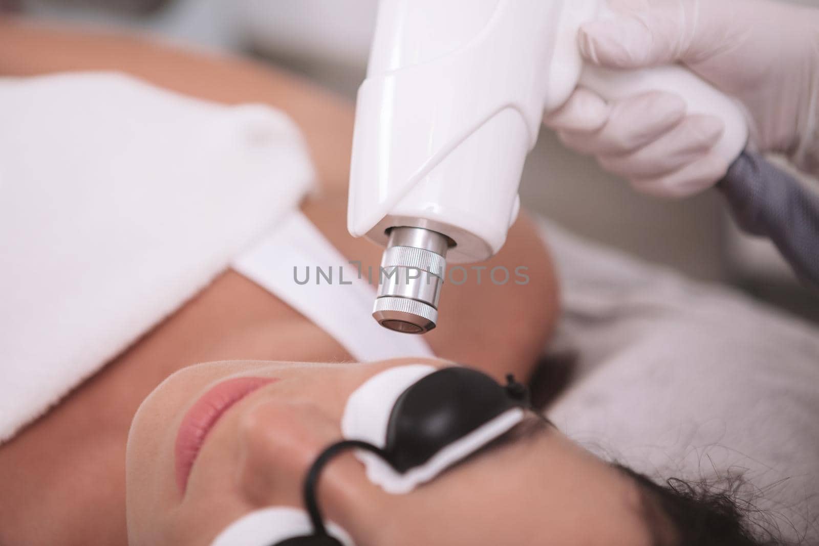 Cropped close up of a beautician doing facial hair laser removal procedure on a female client. Woman getting laser skincare treatment at beauty clinic