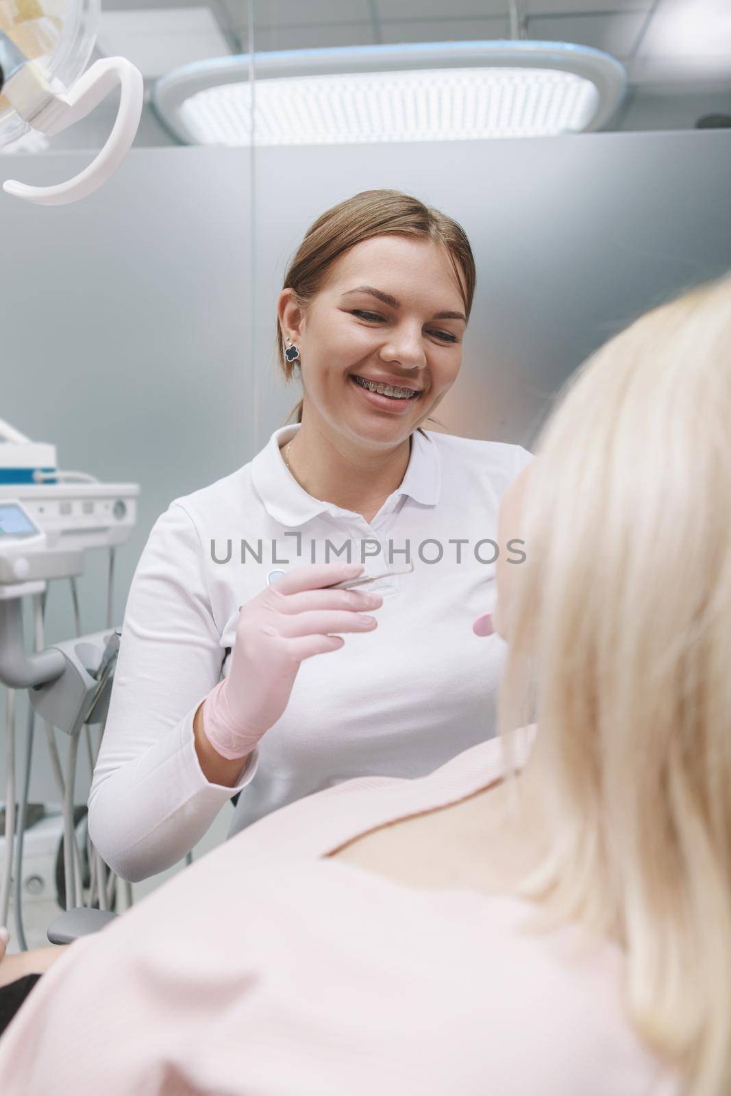 Vertical shot of a female dentist laughing, talking to patient