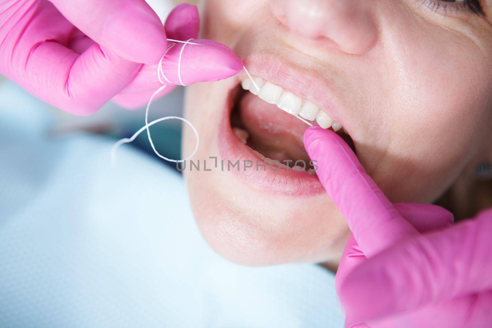 Cropped close up of a dentist using dental floss, cleaning teeth of patient