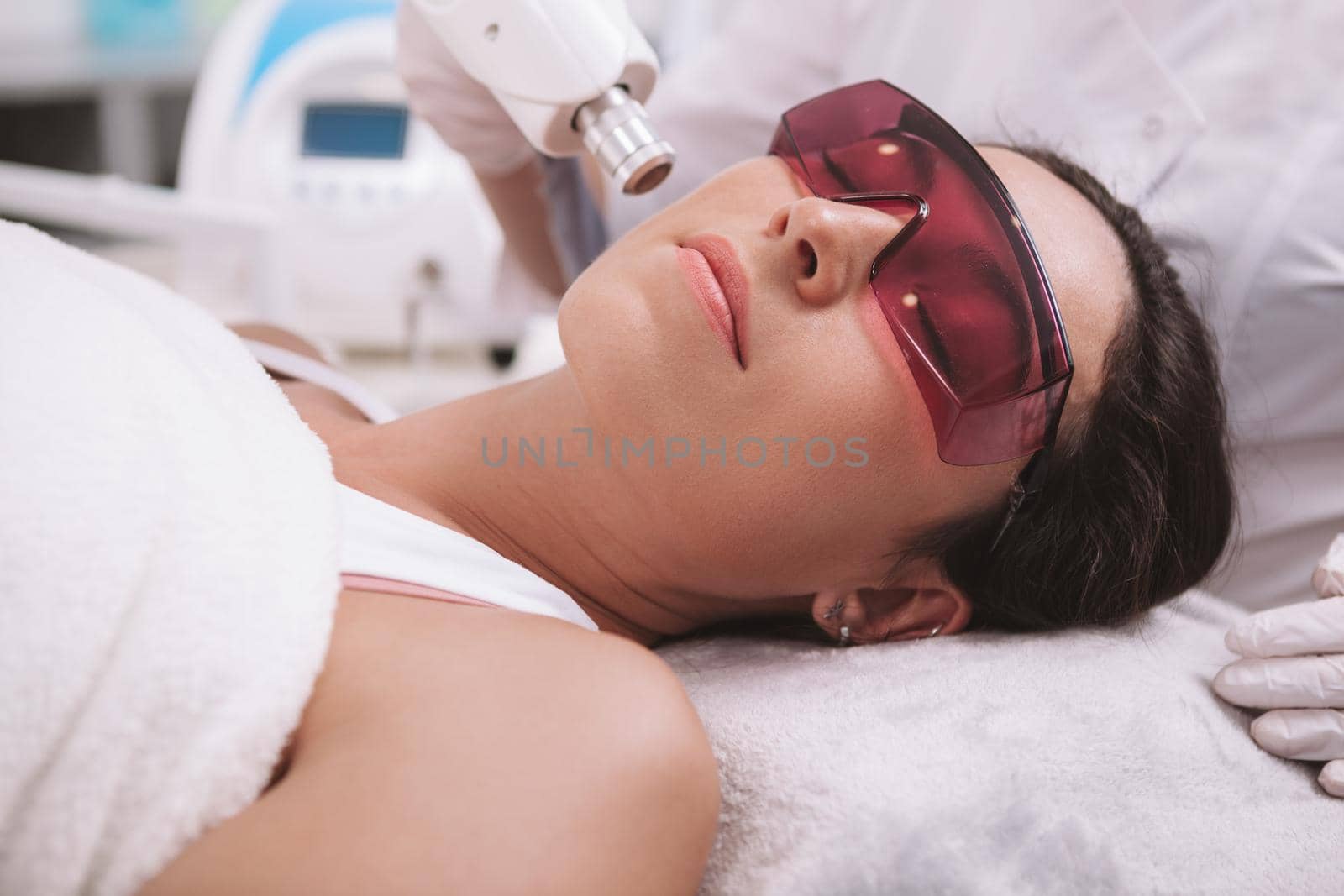 Beautiful young woman getting laser skin treatment at beauty clinic by MAD_Production