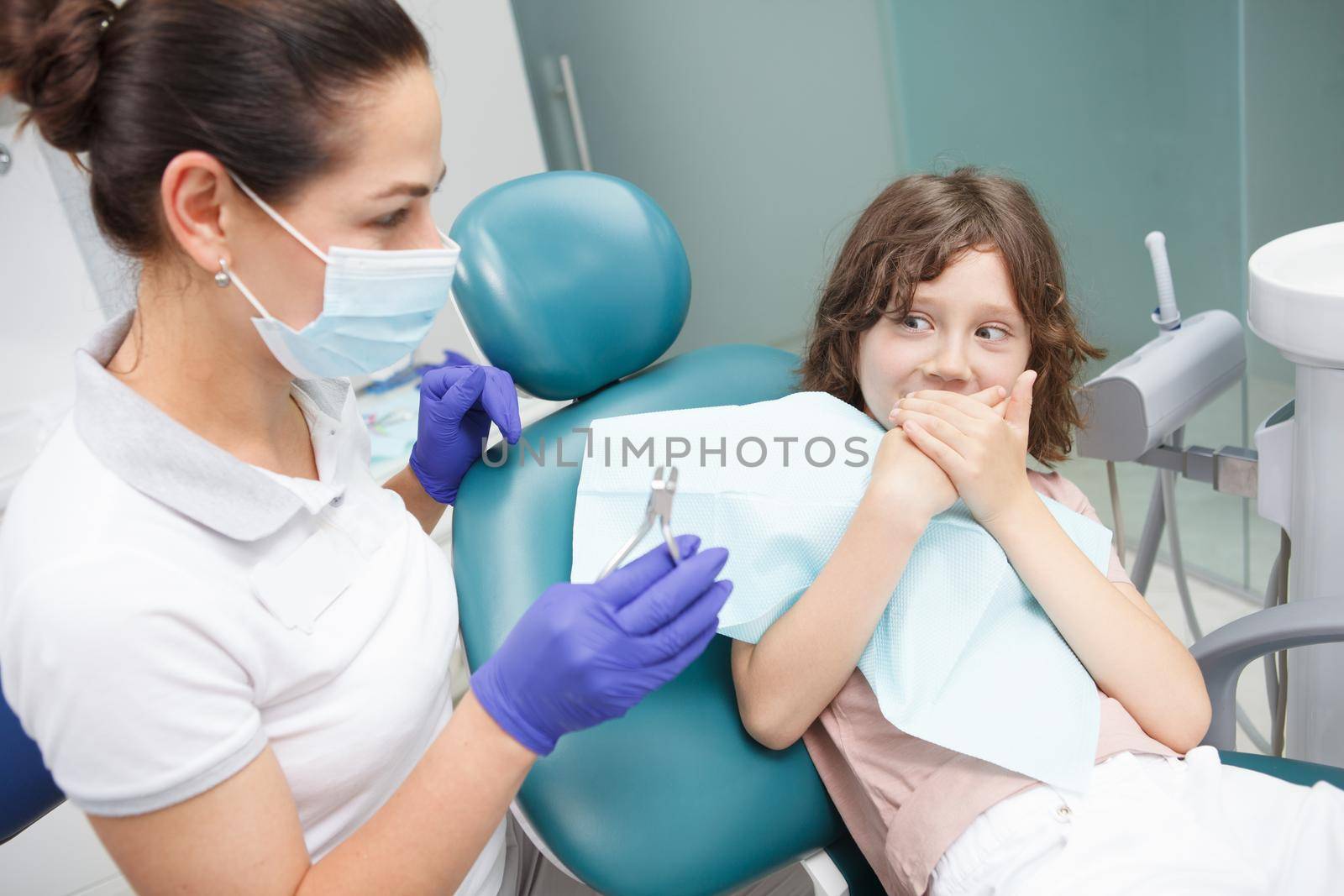 Scared boy refusing to open his mouth for dental examination at the clinic