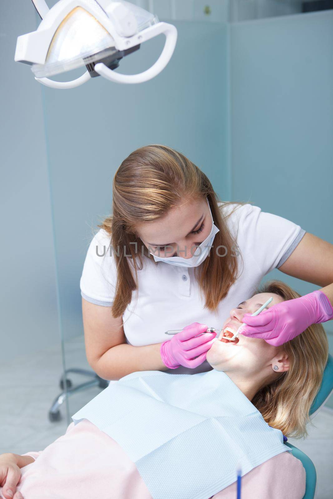 Vertical shot of a professional dentist examining teeth of female patient