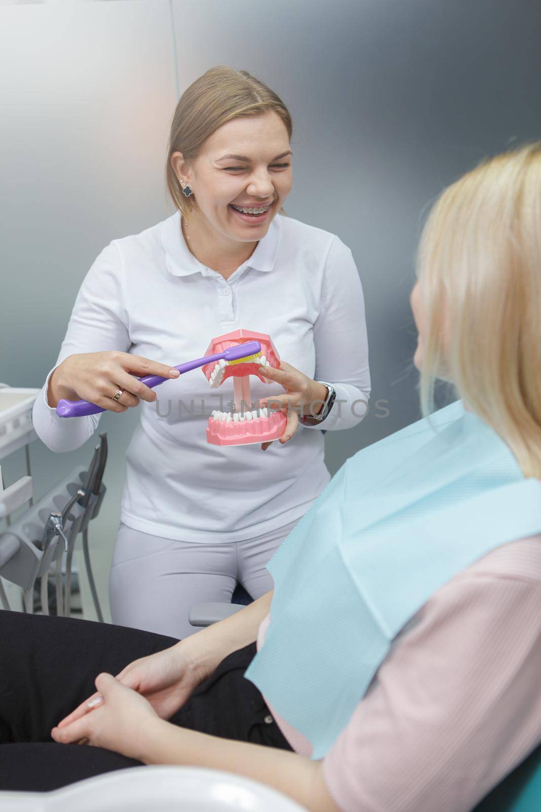 Vertical shot of a female dentis showing her patient how to brush teeth correctly on jaw model