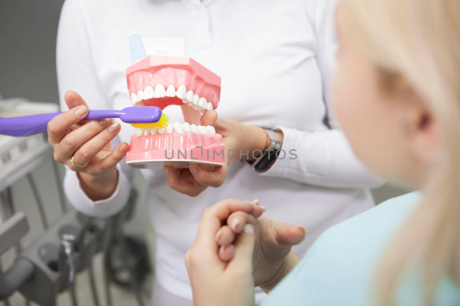 Cropped shot of a female dentist showing her patient how to brush teeth correctly, using denture model