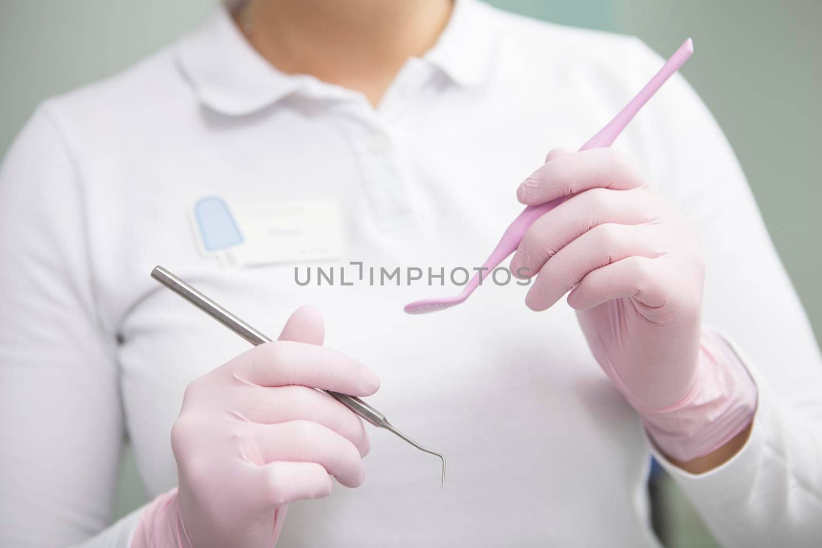 Unrecognizable female dentist wearing medical rubber gloves, holding dental tools
