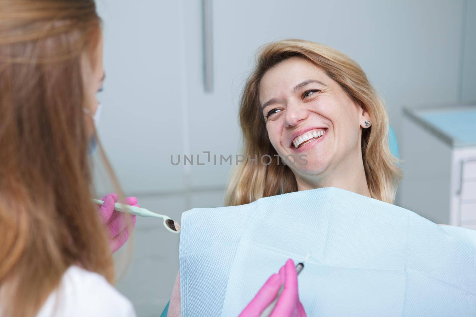 Happy mature woman laughing, talking to her dentist during dental appointment
