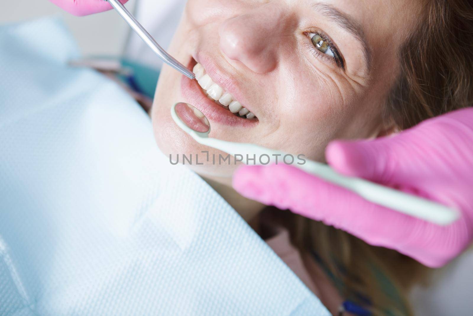 Cropped close up of dentist checking teeth of mature female patient