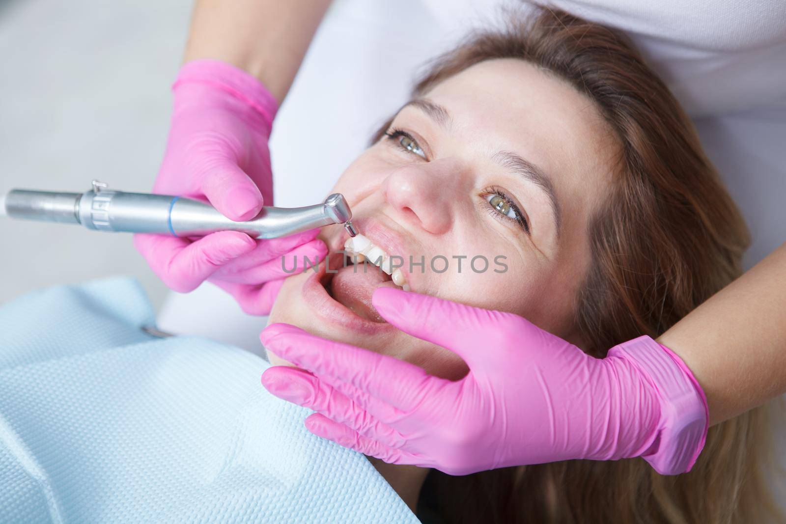 Unrecognizable dentist doing professional dental cleaning of teeth of mature woman