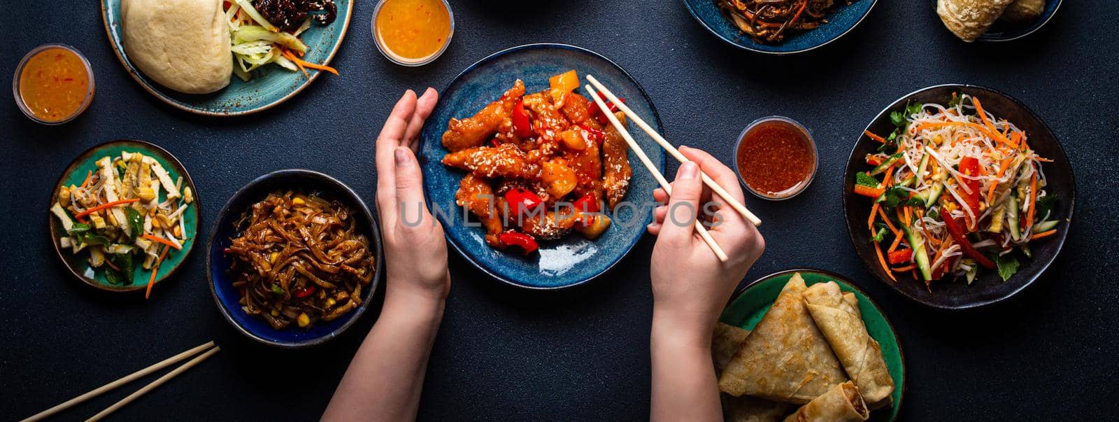 Set of Chinese dishes on table, female hands holding chopsticks by its_al_dente