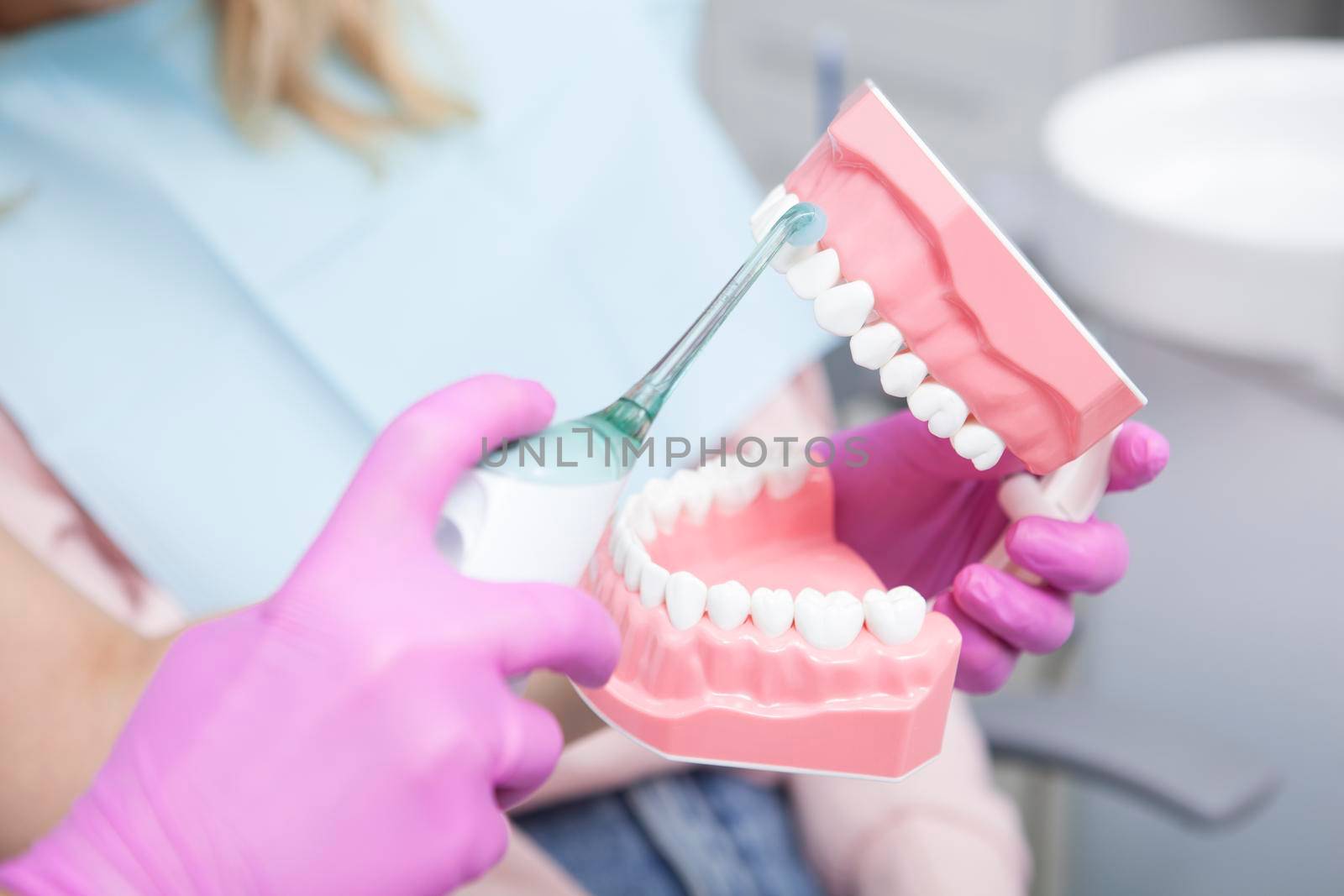 Cropped shot of unrecognizable dentist showing her patient how to clean teeth with ultrasonic toothbrush on jaw model