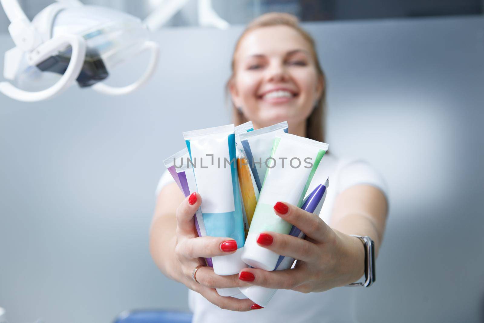 Selective focus on many toothpaste tubes cheerful female dentist holding out to the camera