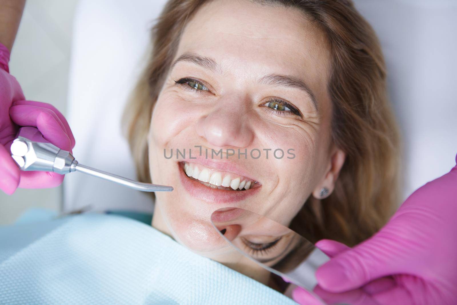 Close up of a cheerful mature woman smiling while dentist examining her teeth