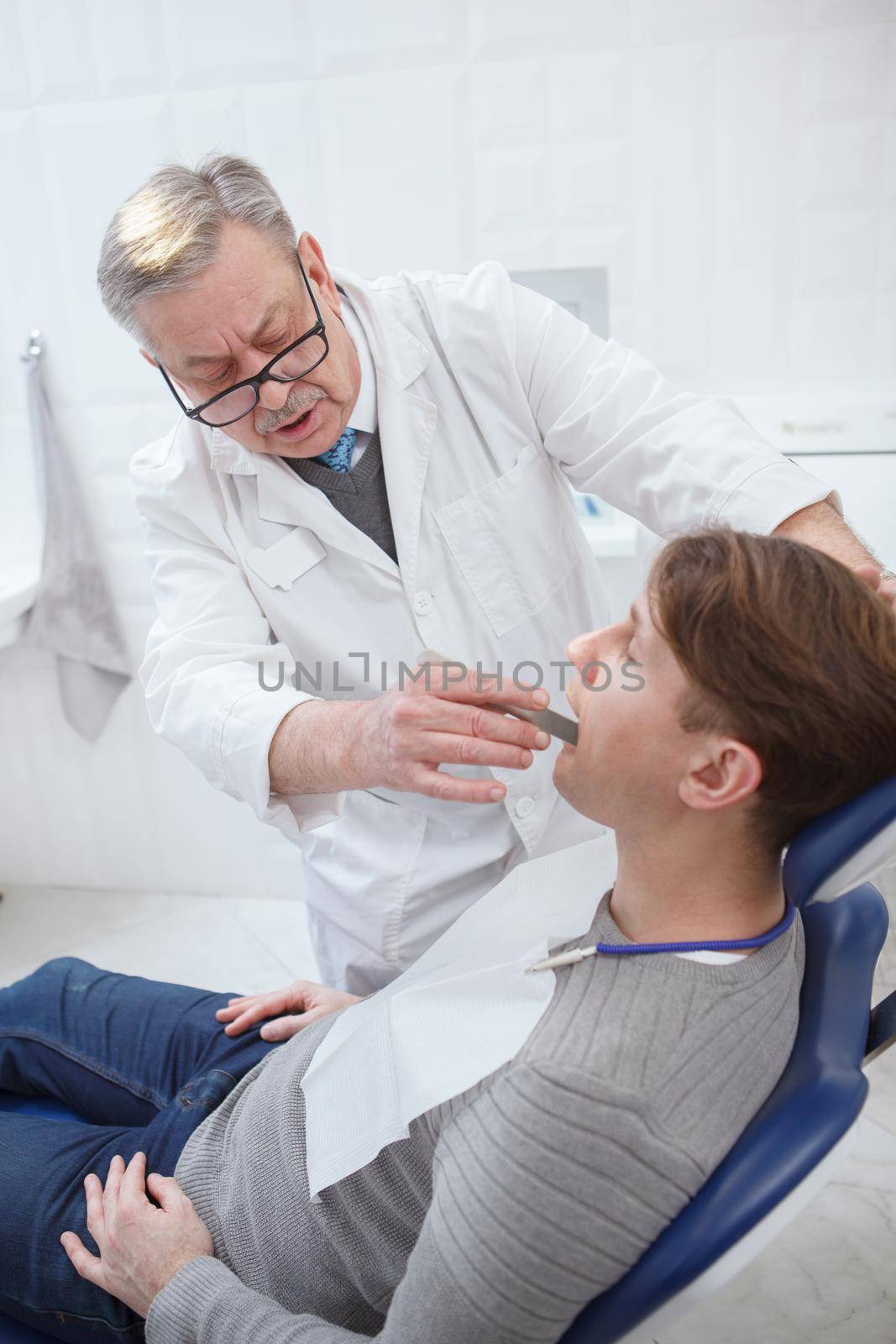 Senior dentist working at his clinic by MAD_Production