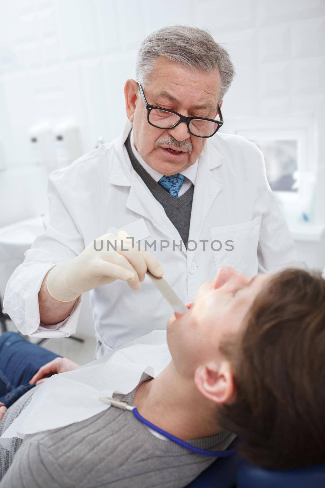 Senior dentist working at his clinic by MAD_Production