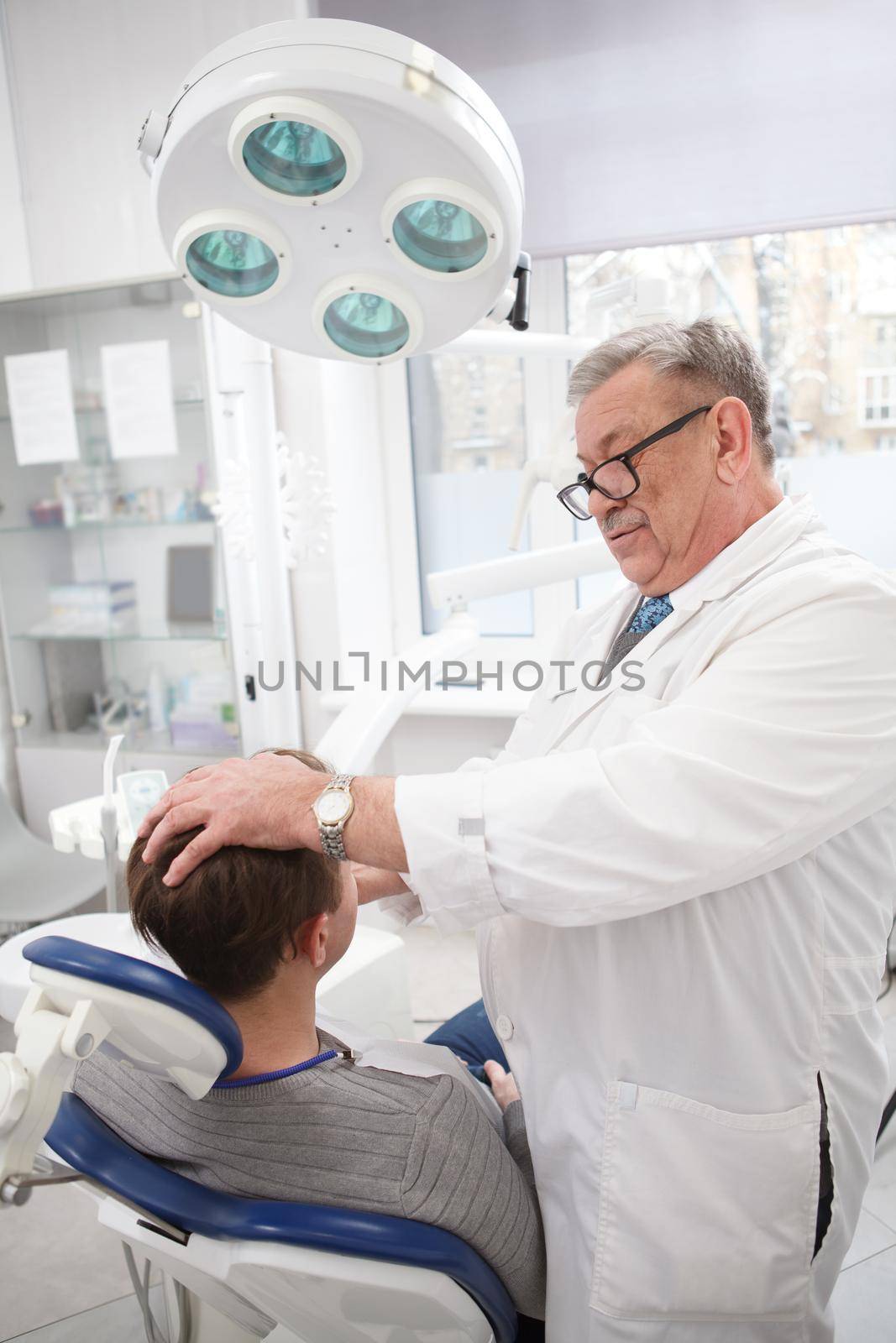Senior dentist working at his clinic by MAD_Production