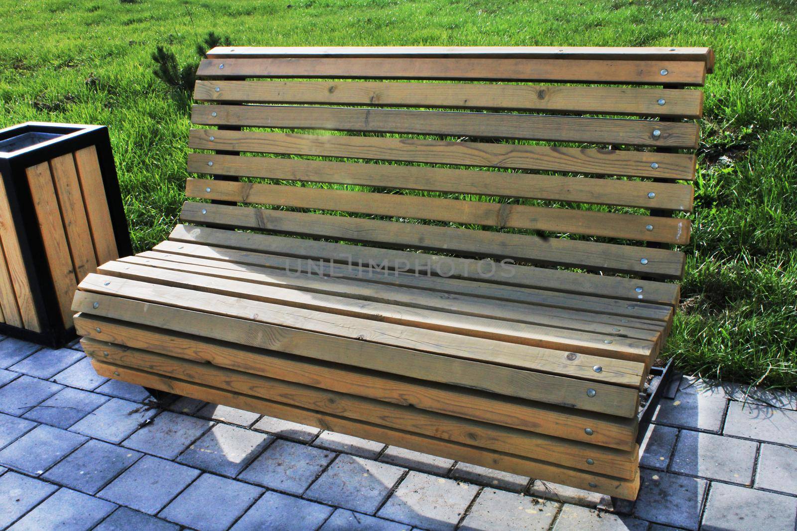 Light wooden bench and urn in the city park close-up. Urban architecture.