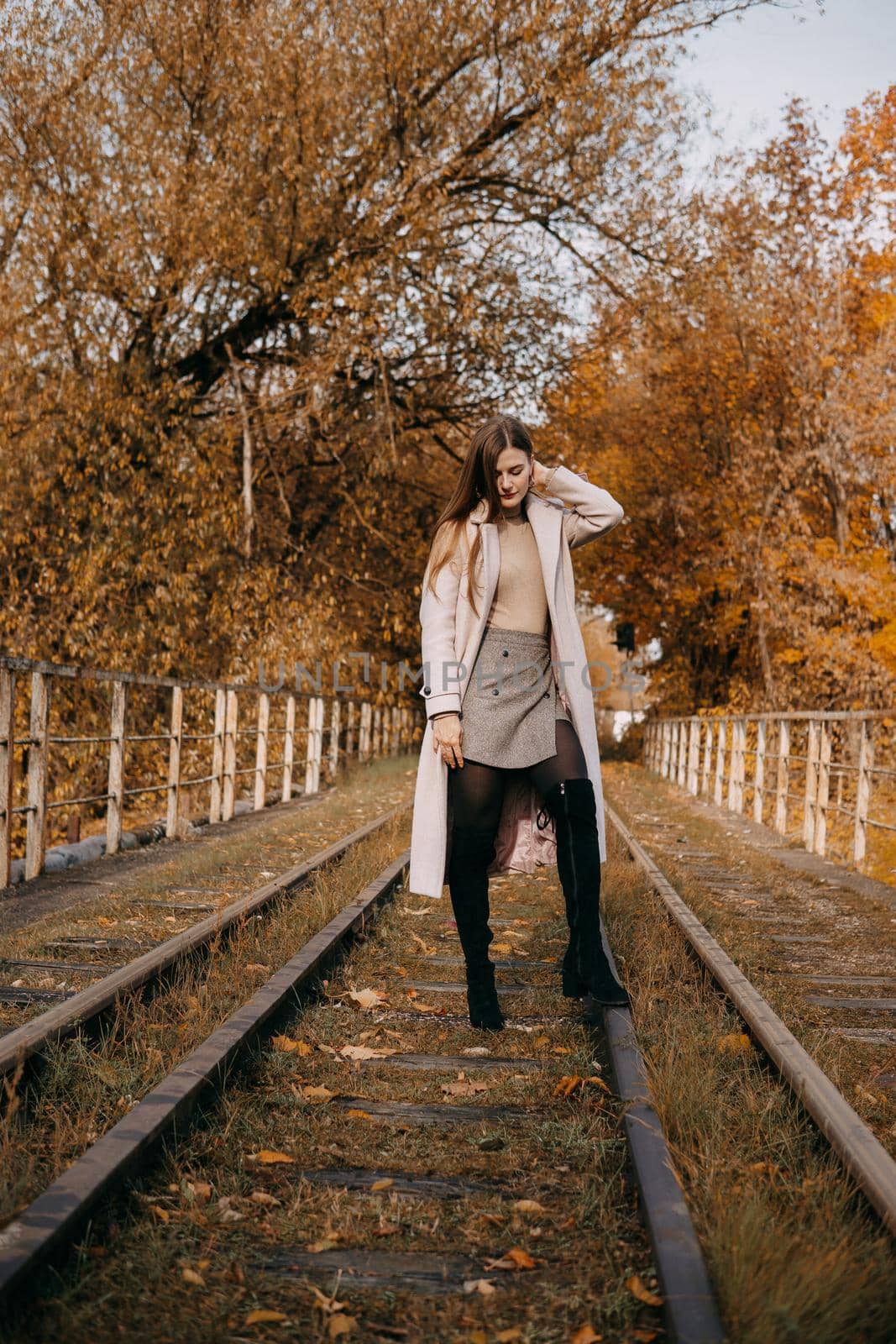 beautiful long-haired woman walks through the autumn streets. Railway, autumn, woman in a coat. by Annu1tochka