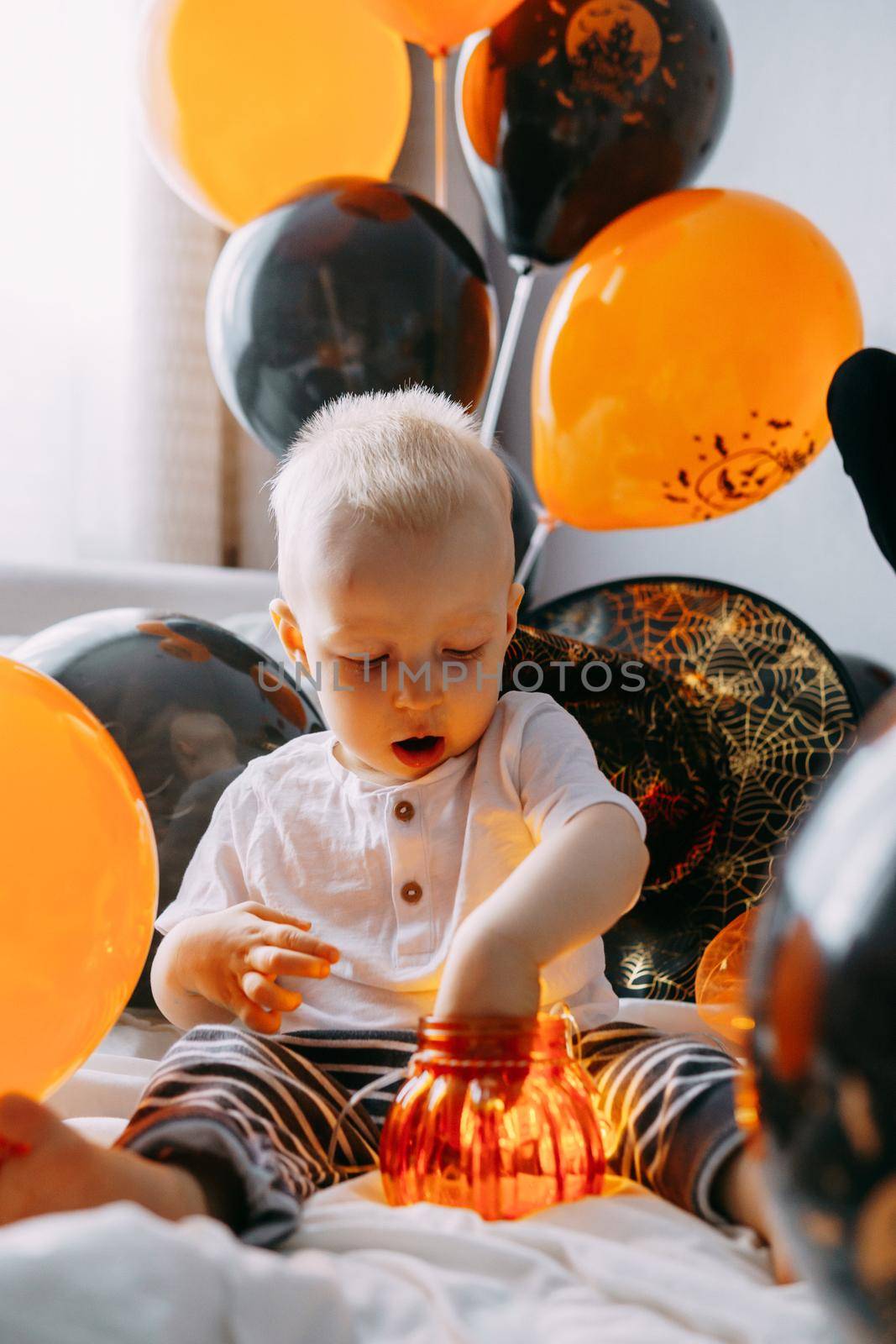 Children's Halloween - a boy in a carnival costume with orange and black balloons at home. Ready to celebrate Halloween