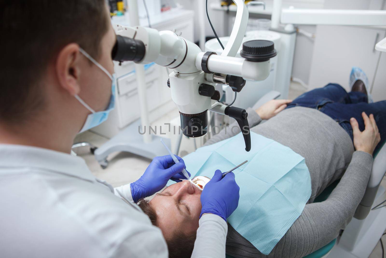 Mature man having dental treatment at the clinic, dentist using microscope