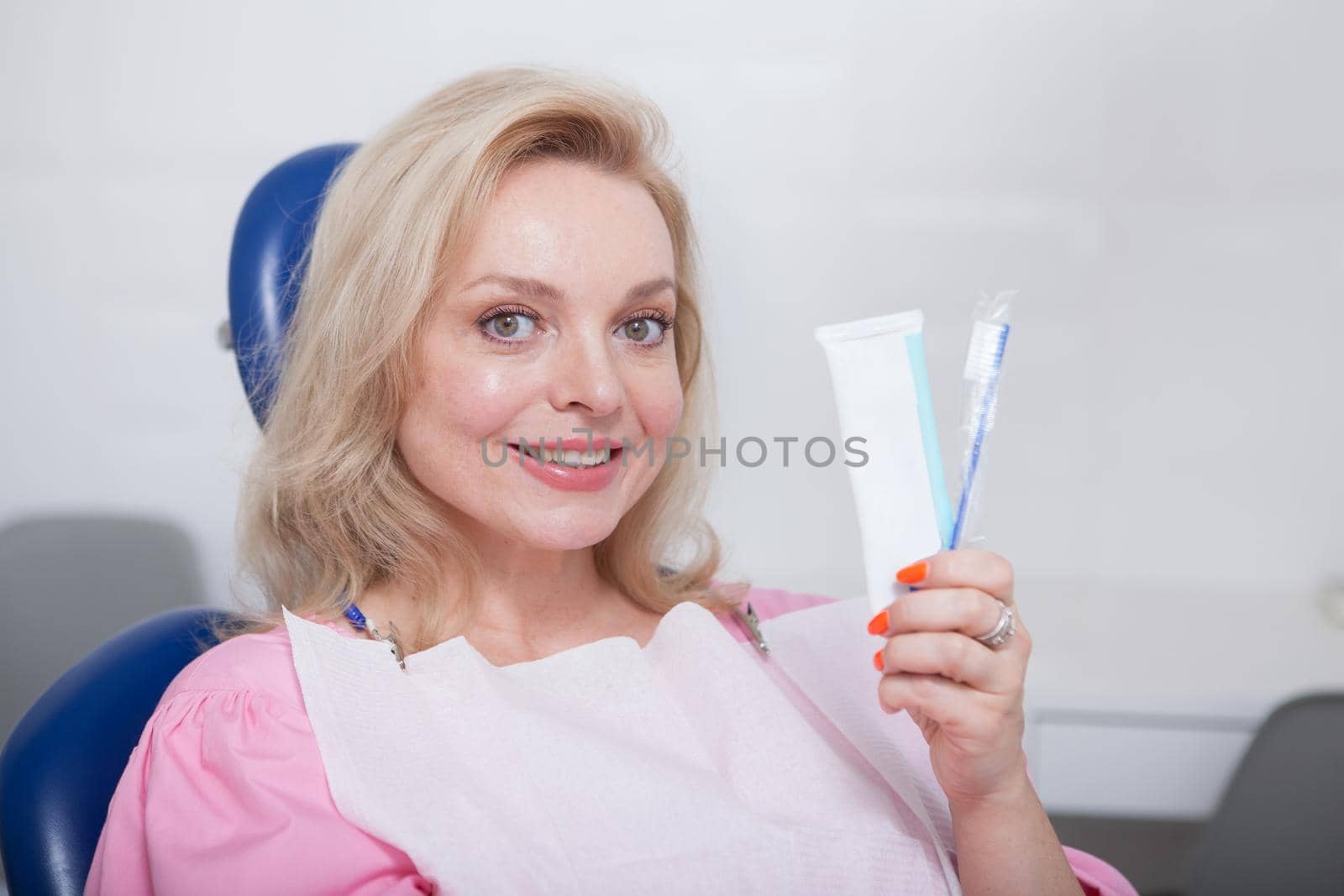 Lovely mature woman smiling, holding toothbrush and toothpaste