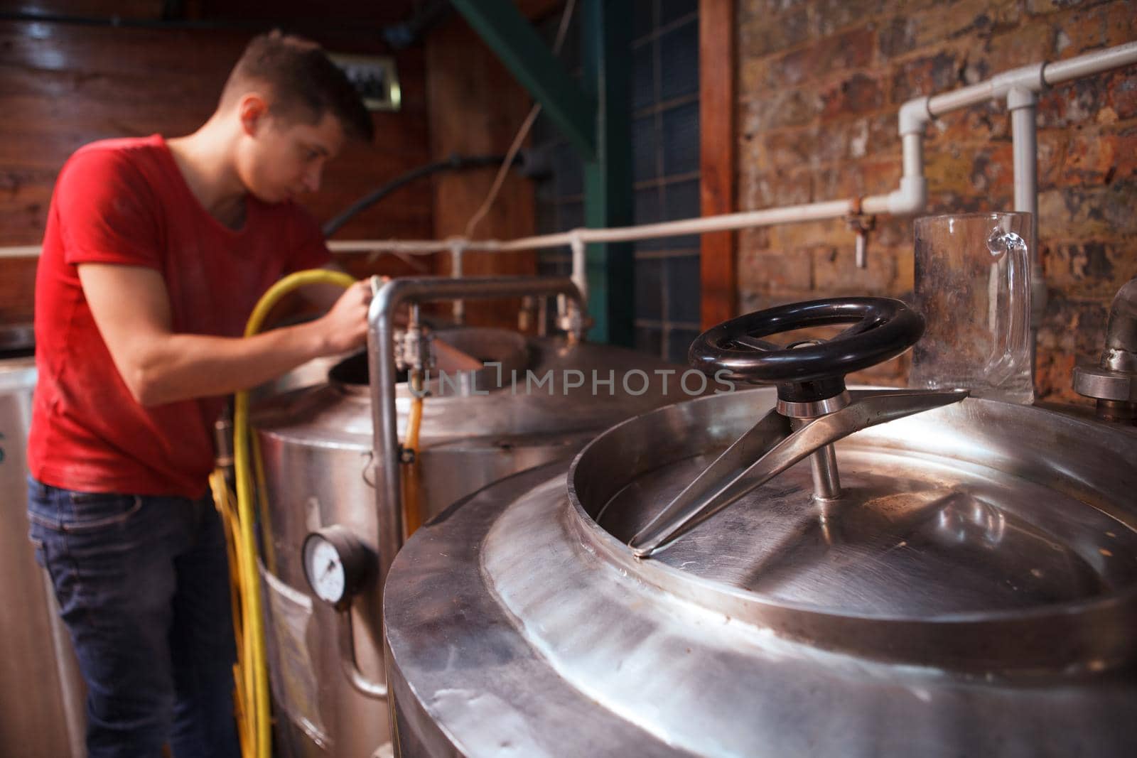 Selective focus on metal beer tank, technician washing inside a container with water hose