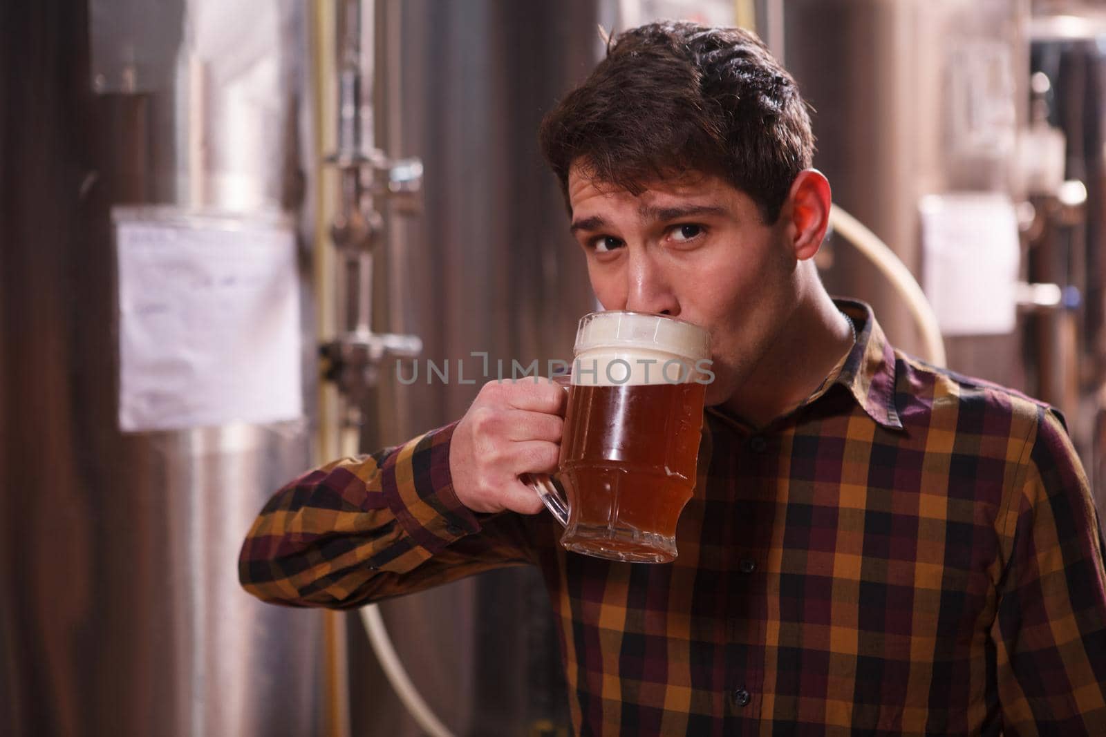 Man sipping delicious craft beer from a mug, looking to the camera