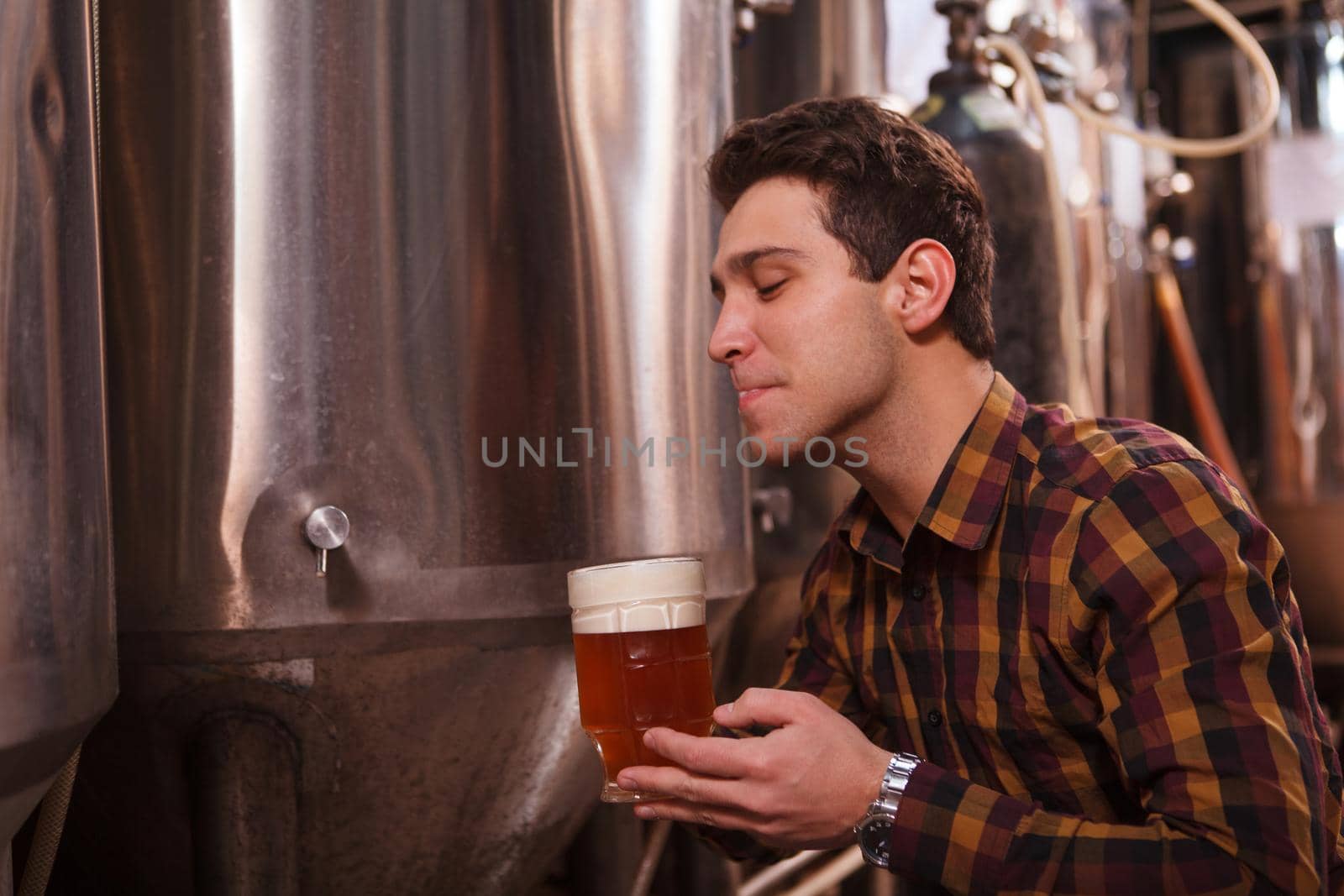 Handsome brewer enjoying drinking delicious craft beer at his microbrewery