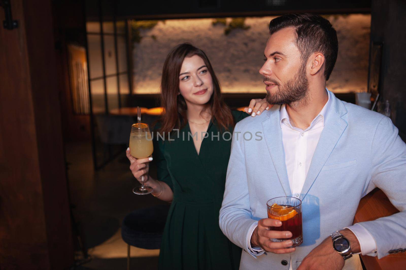 Beautiful woman approaching handsome elegant man at the bar. Young woman flirting with a guy at night club