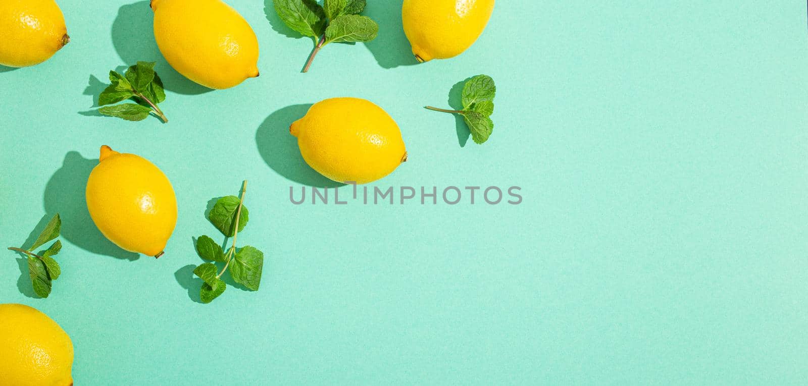 Lemons with mint on minimal blue background sun light hard shadows pattern background by its_al_dente