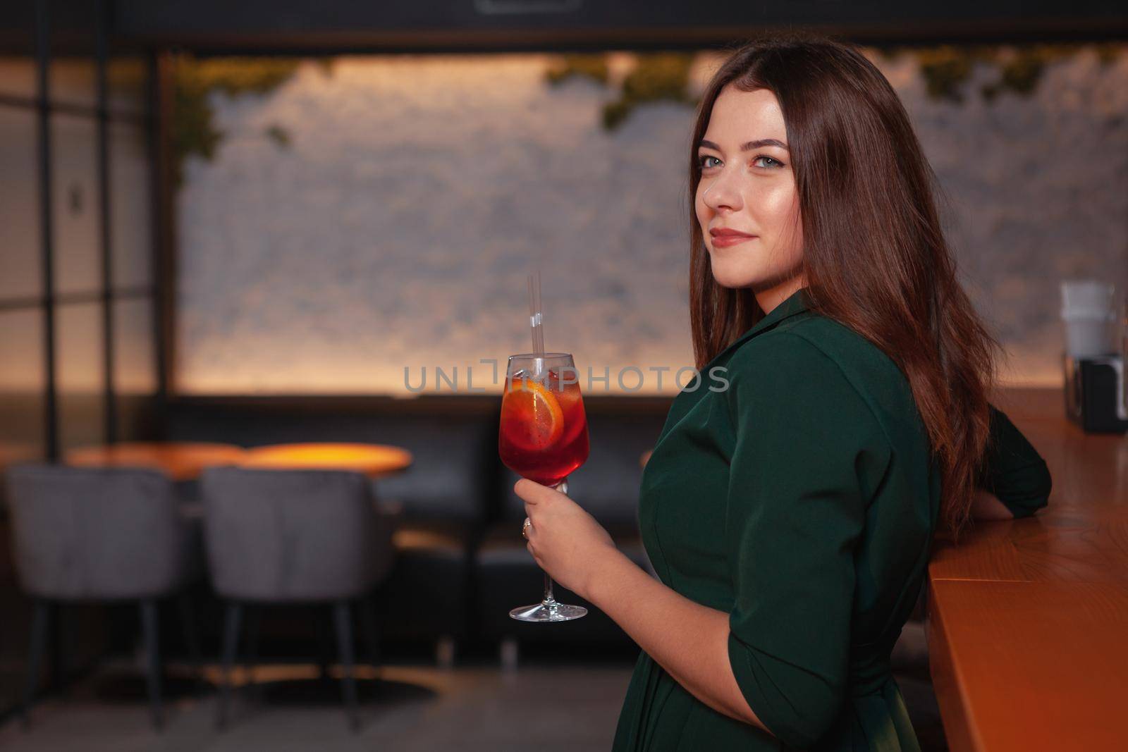 Attractive classy woman having a drink at the bar in the evening