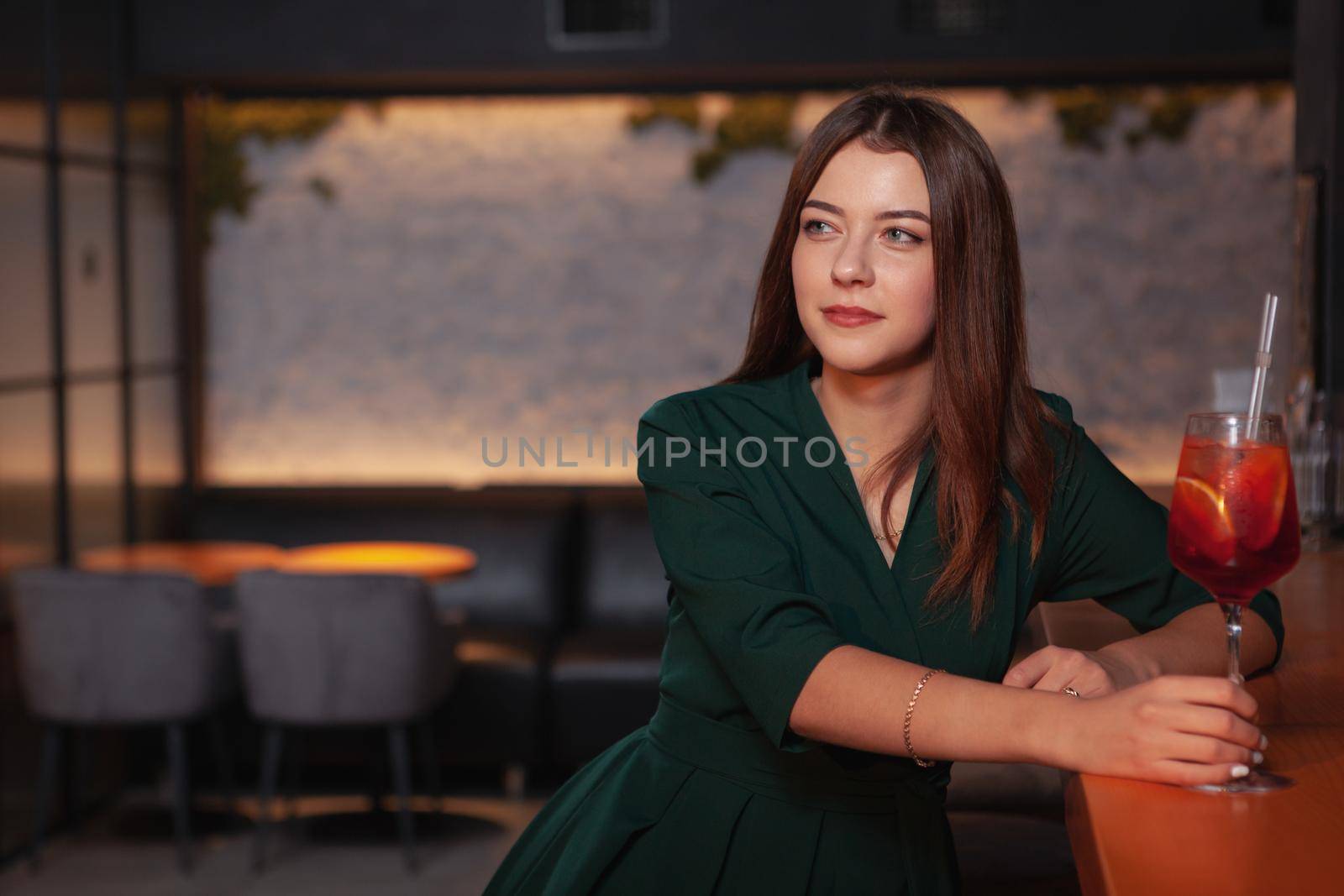 Beautiful young woman enjoyinf relaxing at the bar, having a cocktail, copy space