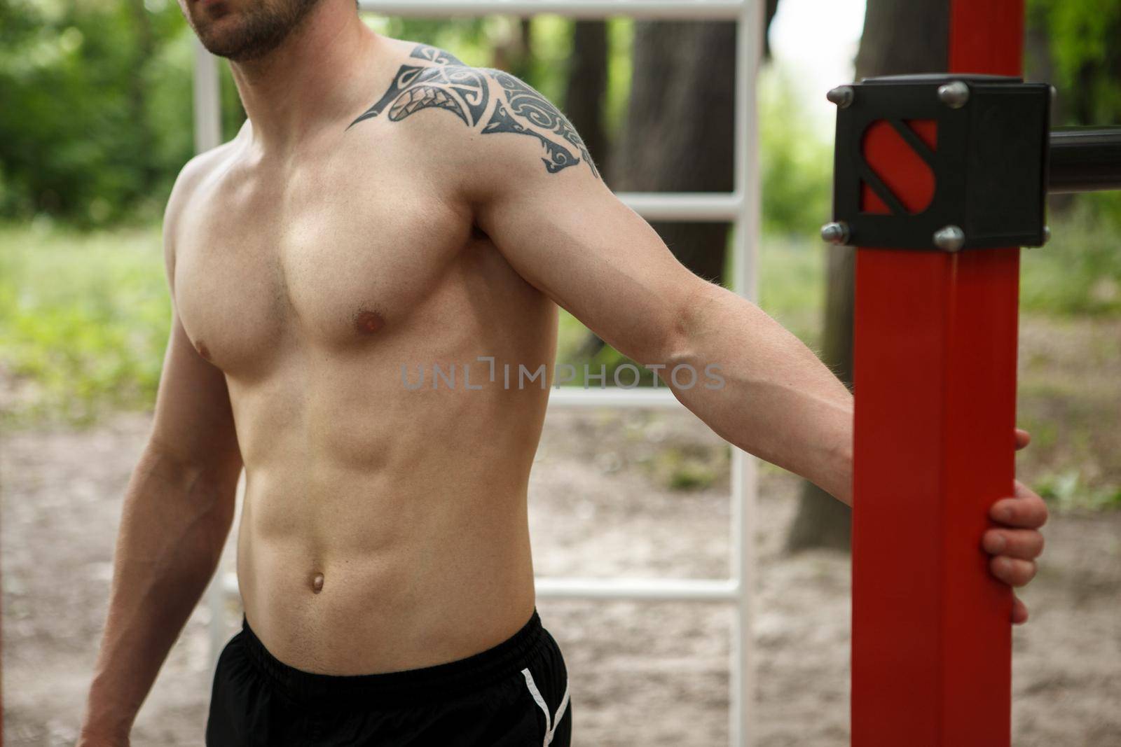 Cropped shot of a muscular shirtless athletic man resting during outdoor workout