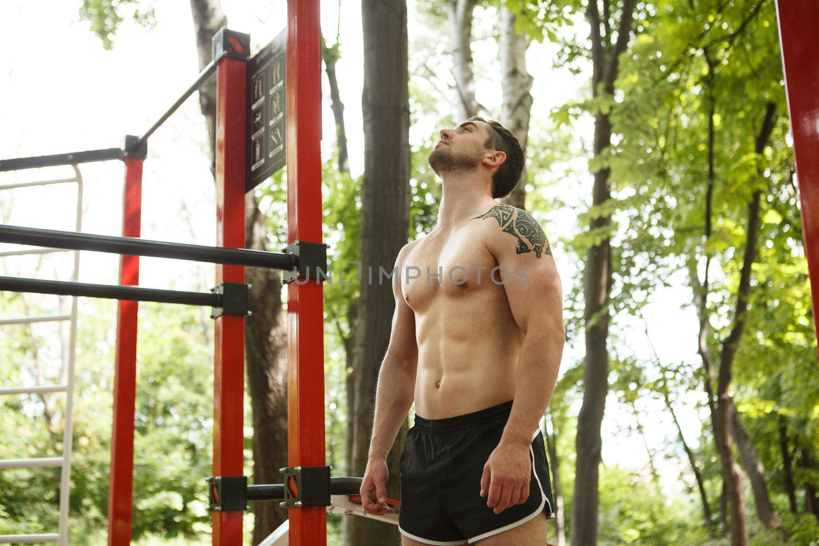 Low angle shot of a shirtless sexy male athlete with perfect muscular body, resting after exercising outdoors