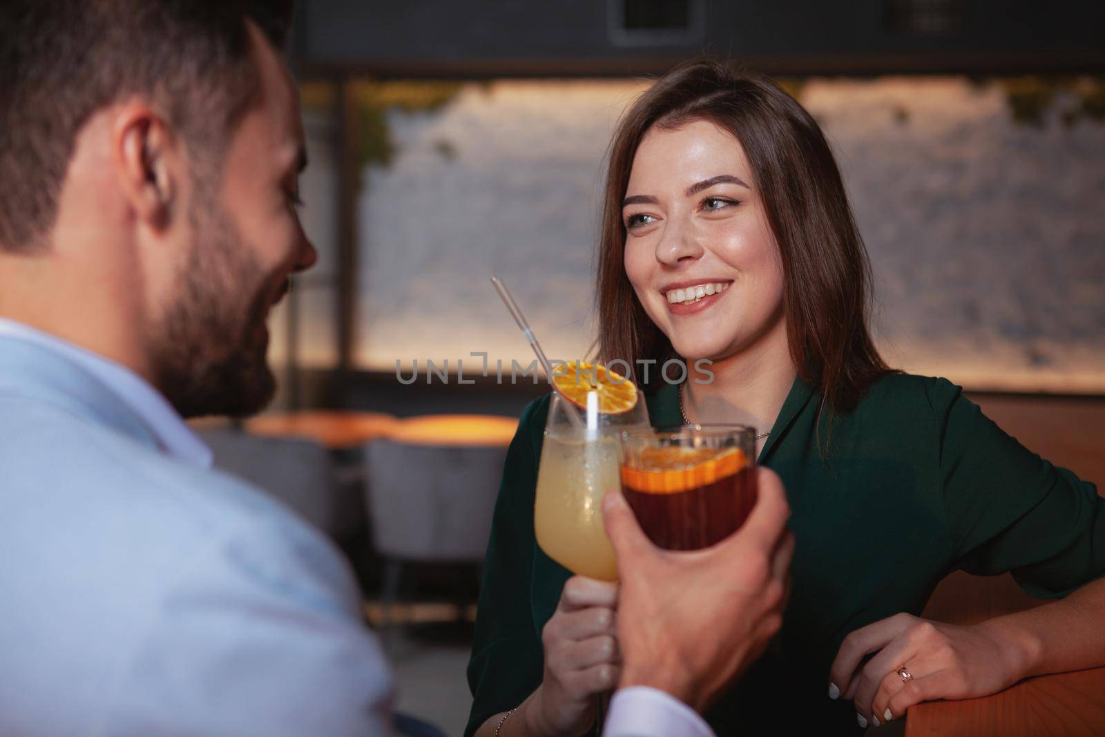 Beautiful cheerful woman enjoying night out with her boyfriend at cocktail bar. Couple celebrating anniversary