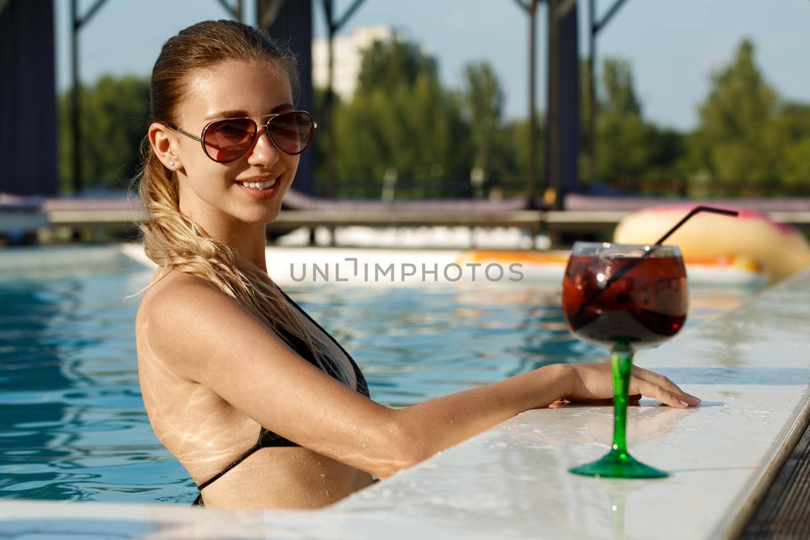 Young woman relaxing in the swimming pool by MAD_Production